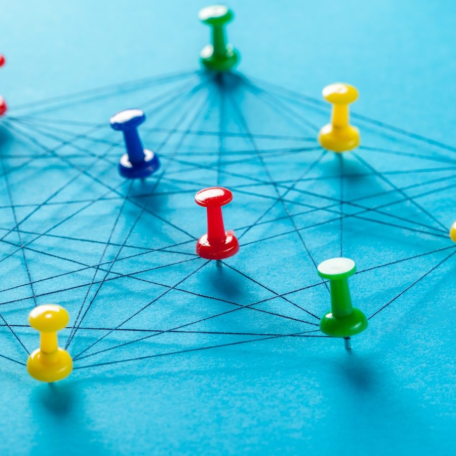 Colored push pins connected by black string forming a network on a blue background—reminiscent of businesses navigating the complexities of domain management.